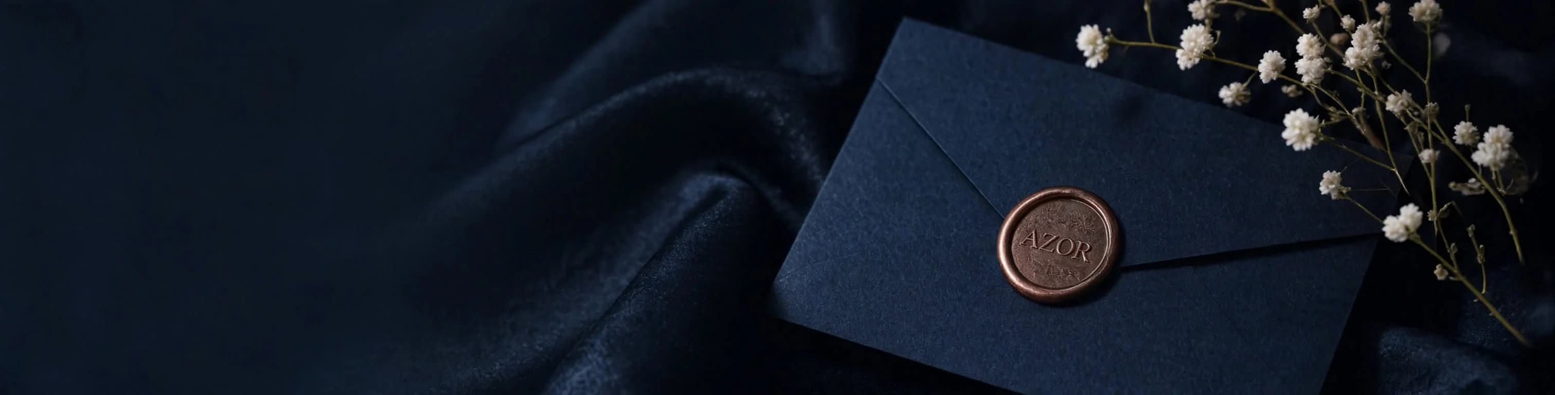 Black envelope sealed with bronze Azor wax stamp on black silk drapery with white florals