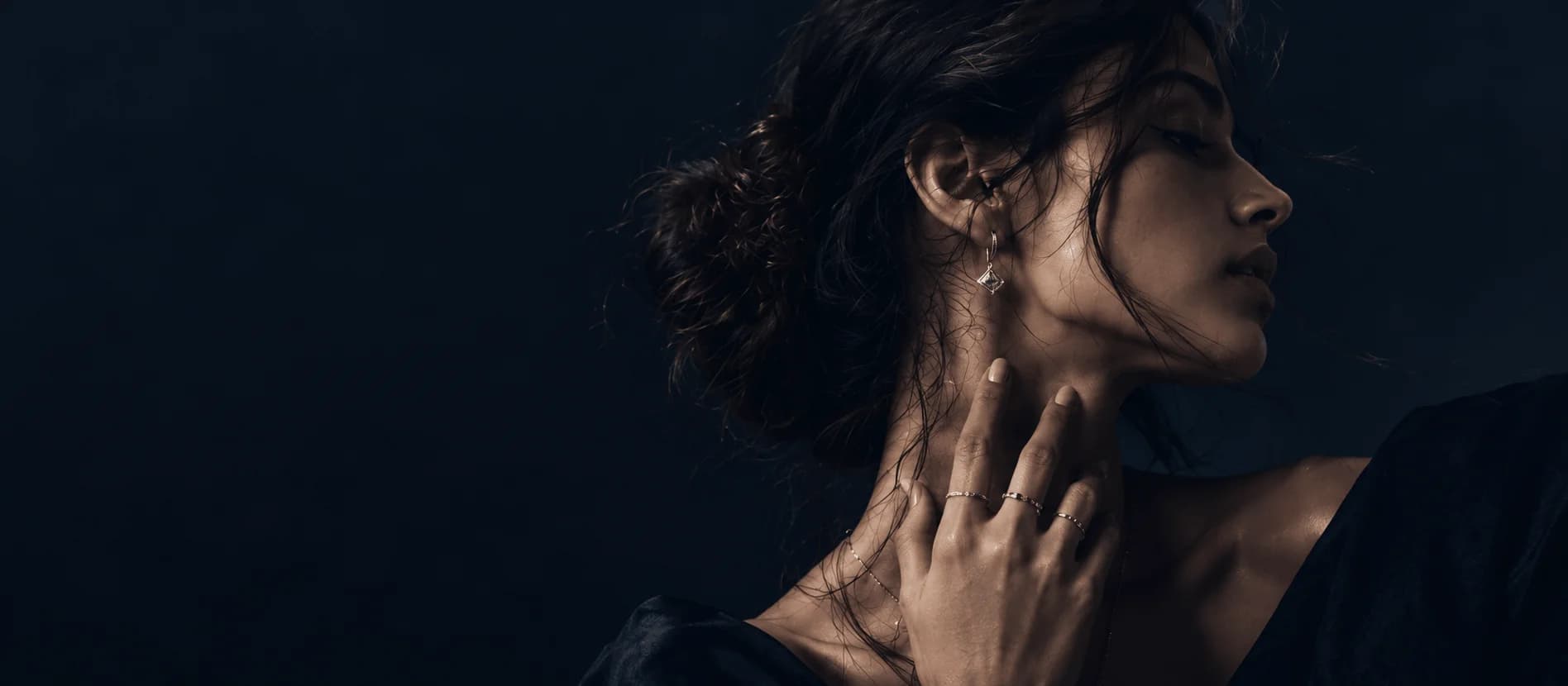 Clean studio portrait of a woman wearing classic round brilliant diamond solitaire necklace and solitaire ring